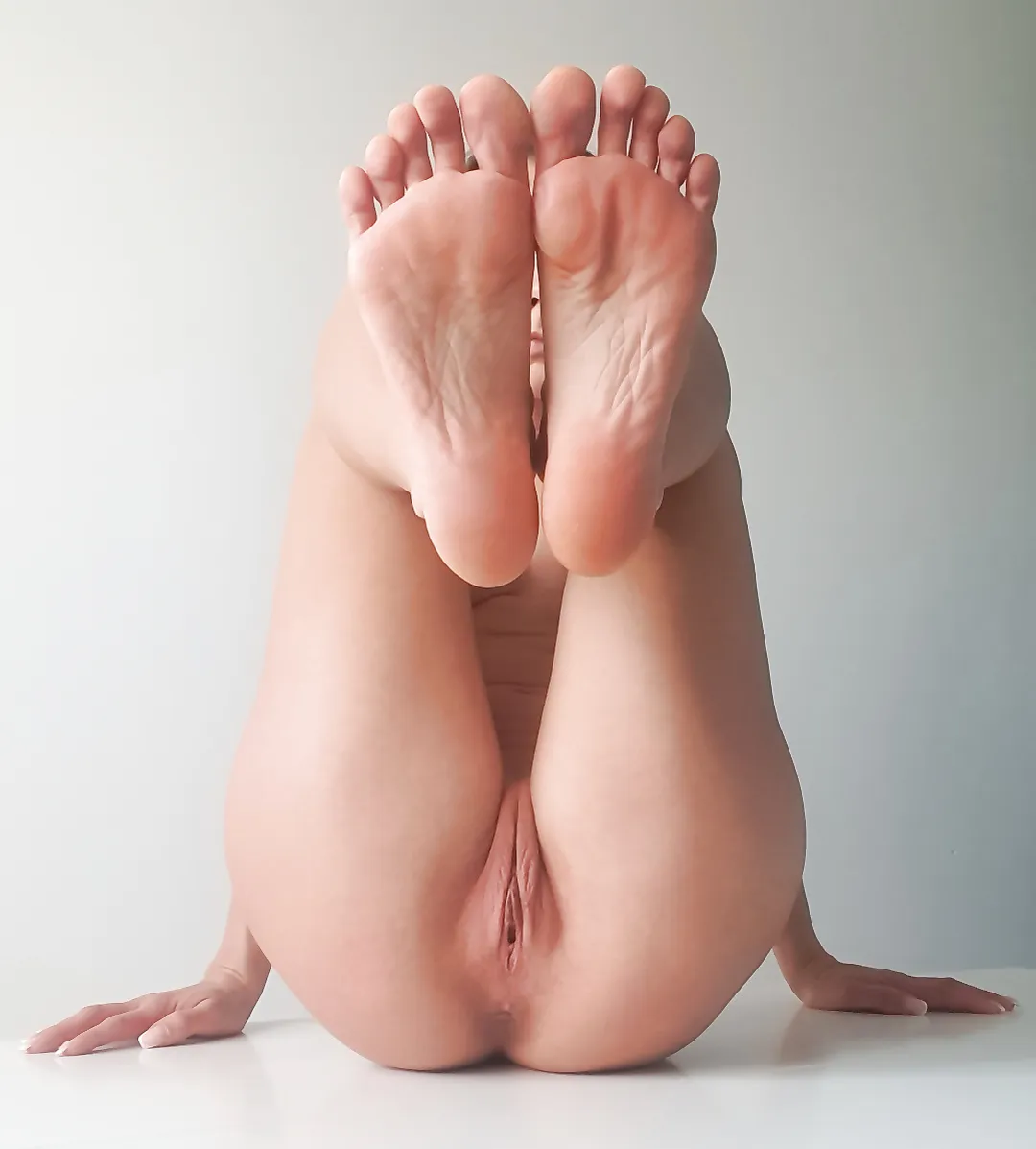 A girl lying down with her legs spread wide, showing off her bare pussy.